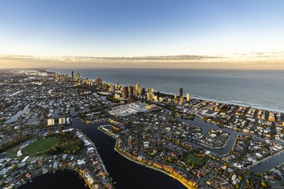 A wide aerial view of the Gold Coast, showcasing its extensive canal suburb network and beachside skyline.