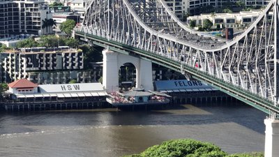 A close aerial view of the Story Bridge arch with Howard Smith Wharves restaurants below, Brisbane.
