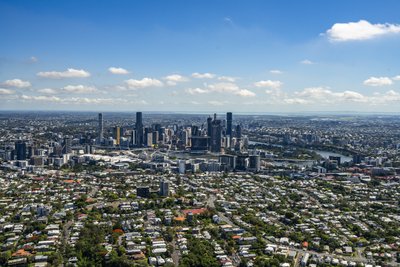 Aerial view of Brisbane city centre and suburbs extending to the horizon on a sunny day.