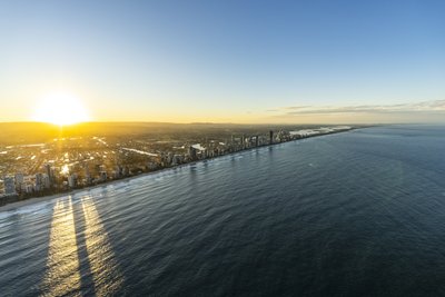 Aerial view of the Gold Coast at sunrise with tower shadows stretching across the Pacific Ocean.