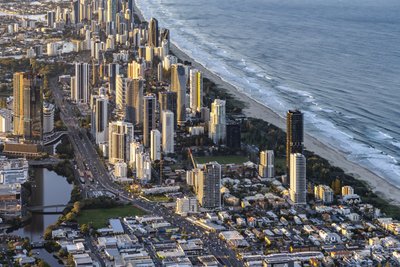 Aerial view of Gold Coast Broadbeach skyline at golden hour with Nerang River canal and beach.