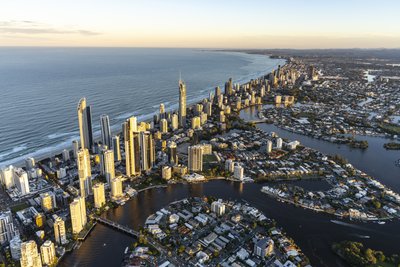 A close aerial view of Surfers Paradise and Q1 Tower at morning with Nerang River canals and beach.