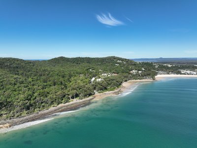 Aerial view of Noosa Heads showing Little Cove, forested headland with luxury homes nestled in the trees and Noosa township beyond.