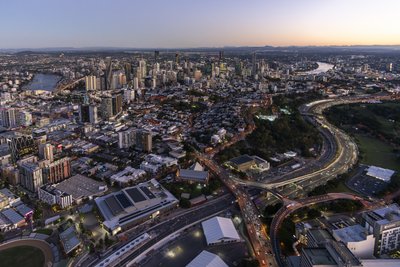 Aerial dusk view of South Brisbane, showing the Pacific Motorway with light trails and the CBD skyline.