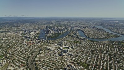 A wide aerial view of greater Brisbane, showcasing the CBD and winding Brisbane River through surrounding suburbs.