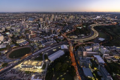 Aerial dusk view of Brisbane city with Pacific Motorway and RNA Showgrounds visible.