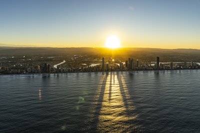 Aerial view of Surfers Paradise at sunrise with the Q1 Tower casting long shadows across the Pacific Ocean, Gold Coast.