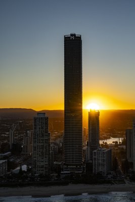 Aerial view of high-rise towers silhouetted against a brilliant orange sunset sky above the beach on Queensland's Gold Coast.