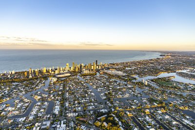 A high aerial view of the Gold Coast showcasing its vast canal network suburbs, with Surfers Paradise skyline in the distance.