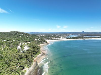 Elevated aerial view of Noosa from the Pacific Ocean, showcasing Main Beach and extending to the hinterland panorama.