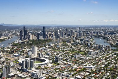 Aerial view of Brisbane featuring the Gabba cricket stadium and CBD skyline along the Brisbane River.