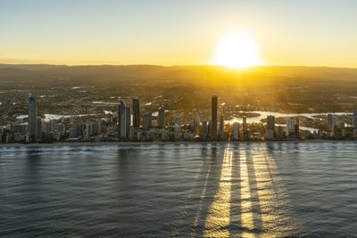 Aerial sunrise view of the Gold Coast coastline with Surfers Paradise tower casting long shadows across the ocean.