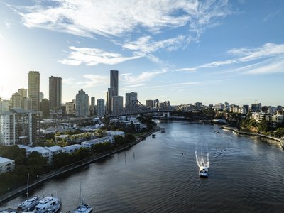 Aerial view of Brisbane River at golden hour with Story Bridge, CityCat ferry and CBD skyline in Kangaroo Point, Queensland.