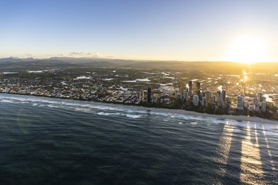 Aerial view from offshore of the Gold Coast beach strip with Surfers Paradise towers at sunrise.