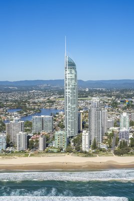 A close-up aerial portrait of the Q1 Tower in Surfers Paradise, Gold Coast with a beach foreground and Nerang River behind.