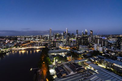 Aerial view of Brisbane CBD at blue hour with glittering city lights reflected on the river.