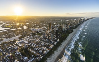 Aerial view of the Gold Coast coastline at sunset, showcasing Surfers Paradise towers and sandy beach.