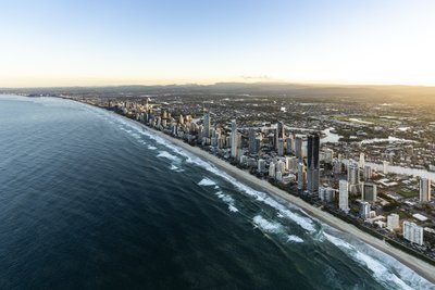 Aerial view of the Gold Coast coastline at morning, featuring high-rise buildings and a golden ocean.