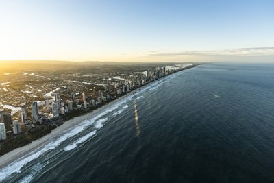 A wide angle aerial view of the Gold Coast coastline from offshore, showcasing the full city strip at early morning.