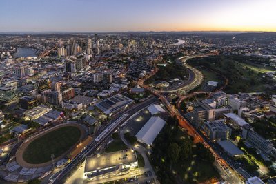 Aerial dusk view of Brisbane with light trails on the Pacific Motorway winding through southern suburbs.