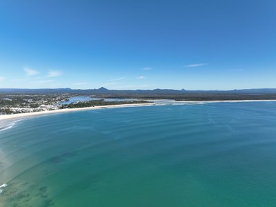 A high-altitude aerial panorama of Noosa, showcasing the township, Main Beach, and Glass House Mountains on the horizon.