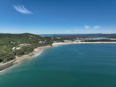 A wide aerial panorama of Noosa showing Main Beach, the town, and surrounding natural landscapes.