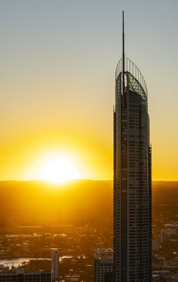 Aerial view of the Q1 tower, Australia's tallest residential building silhouetted against a glowing sunset on the Gold Coast.