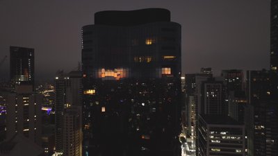 Aerial night view of a dark glass office tower in Brisbane CBD reflecting warm city lights.