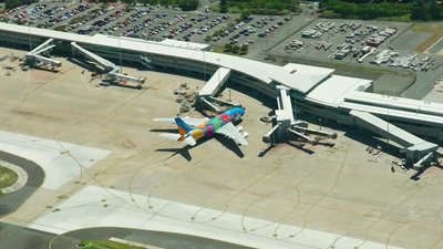 Aerial view of a colorfully branded airline aircraft docked at airport terminal gate, Brisbane.