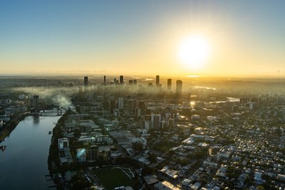 Aerial view over West End, Riverside Drive and the Brisbane City skyline at sunrise.